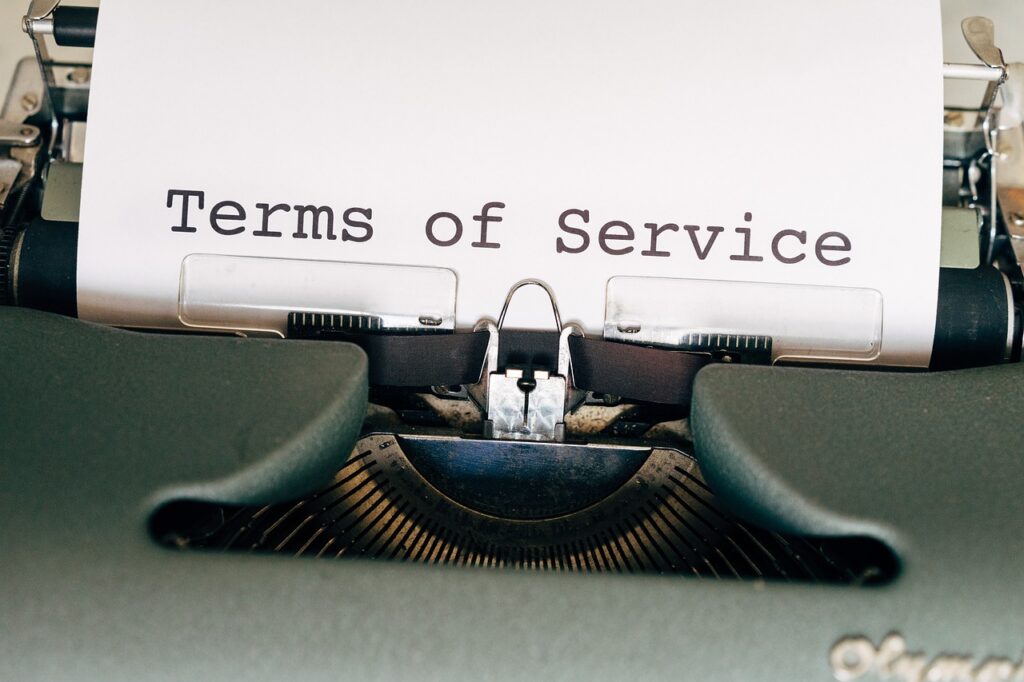  typewriter with a sheet of paper displaying the words "Terms of Service" in bold letters. It signifies the importance of understanding potential pitfalls that new managers need to navigate to avoid liabilities and ensure compliance in their roles.