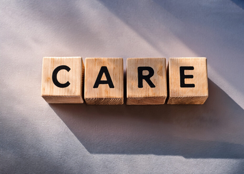 four wooden blocks that say CARE on gray background